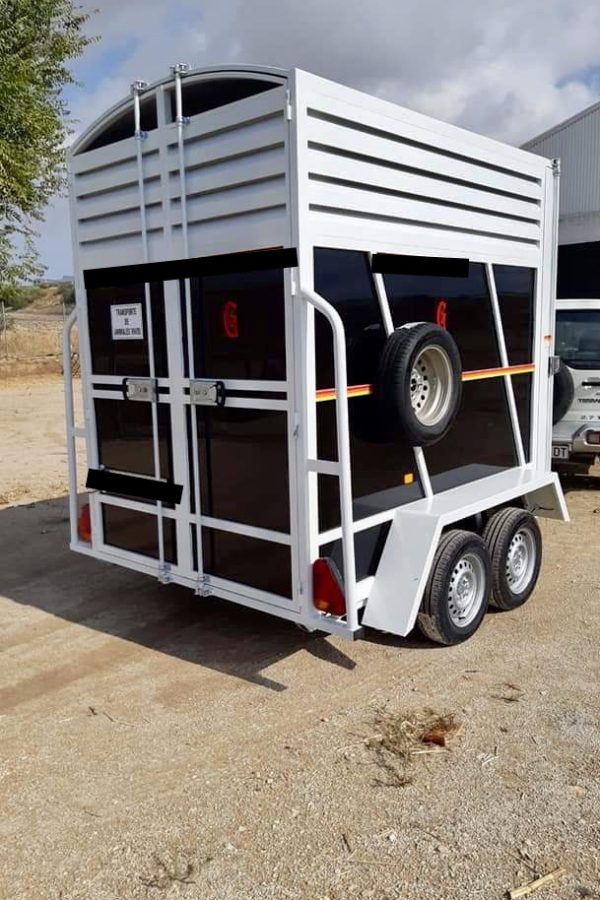 Tipo: Van. Modelo: Caballo y medio y 2 caballos. Medidas: Desde 2.90m x 1.55m x 2.10m de lateral. MMA: 750 kilos. Hasta 3500 kilos. Tara (aprox): 370 kilos. Ruedas: 165- 70 R13 o 185 -70 R14 Cabestrante: Opcional. Lanza: En V de 60 por 60 mm. Reforzada. Tipo de Cabezal: Semiautomático de 1600 kilos. Ejes: 2 unidades de 1000 kilos. Hasta 1800 kilos. Freno: Incluido. Puerta: trasera y lateral en rampa y en apertura lateral. Inst. eléctrica: 7 pines. En caso de matriculación, instalación eléctrica de 13 pines con luz de marcha atrás. Luces: freno, posición, intermitente, antiniebla trasero y gálibo. Luz interior. Material: Hierro soldado y pintado. Rueda de repuesto: Incluido. Rueda jokey: De 60 con brida +30 Euros. Toldo y arquillos en gama a elegir. Guardabarros: De hierro y opcional en fibra. Portamatriculas: Incluido. Seguridad: si, cabezal con llave opcional + 25 euros. Tipo de puerta: Abajo desmontable, lateral o doble hoja +40 Euros. Agarres interiores: Incluidos. Agarres exteriores: Incluido. Incluye montureros, tubos para pecho, culo y separadores. Suelo de chapa de habichuela antideslizante. En madera + 120 euros. Posibilidad de financiación. Otras medidas, pesos consultad.